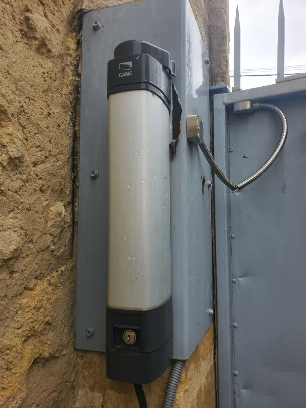 Vérin de motorisation CAME neuf posé sur un pilier en pierre de taille